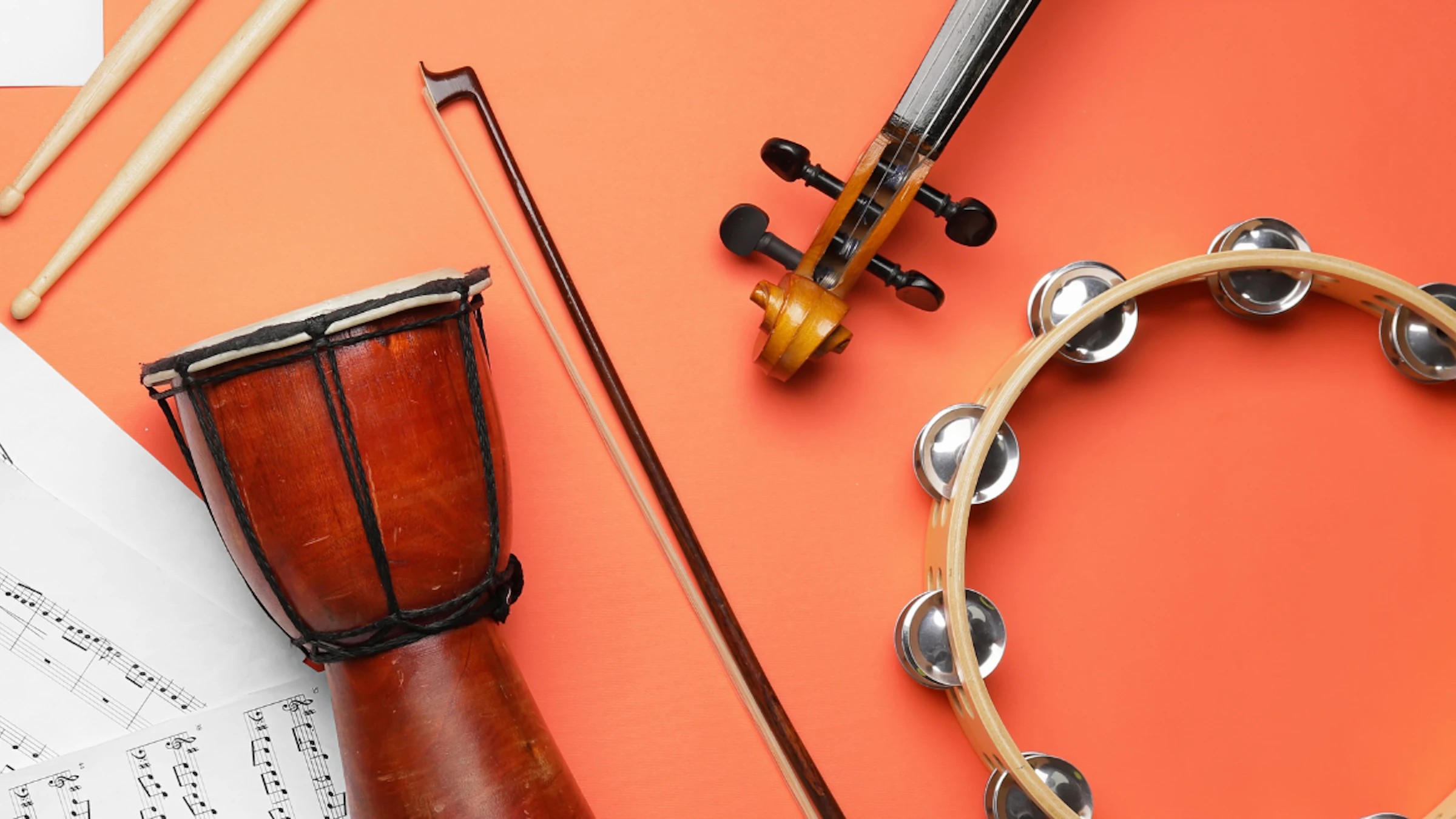 Music instruments and music notes flat lay on a bright orange background